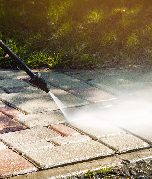 power washing stone patio surface with water spraying for cleaning