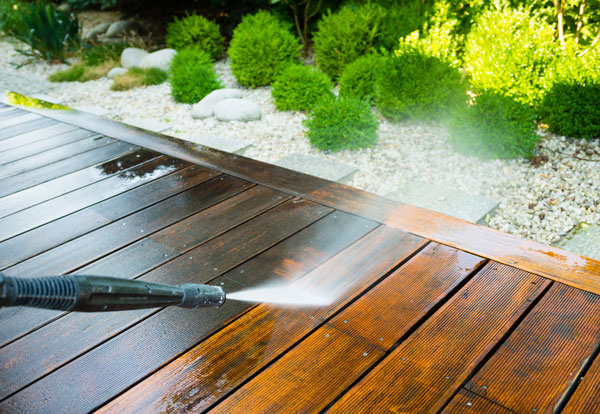power washing wooden deck with water spray cleaning outdoor area
