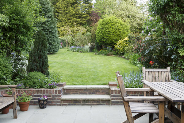lush green garden with neatly trimmed grass colorful flowers and wooden patio furniture features an inviting atmosphere suitable for outdoor relaxation and gatherings